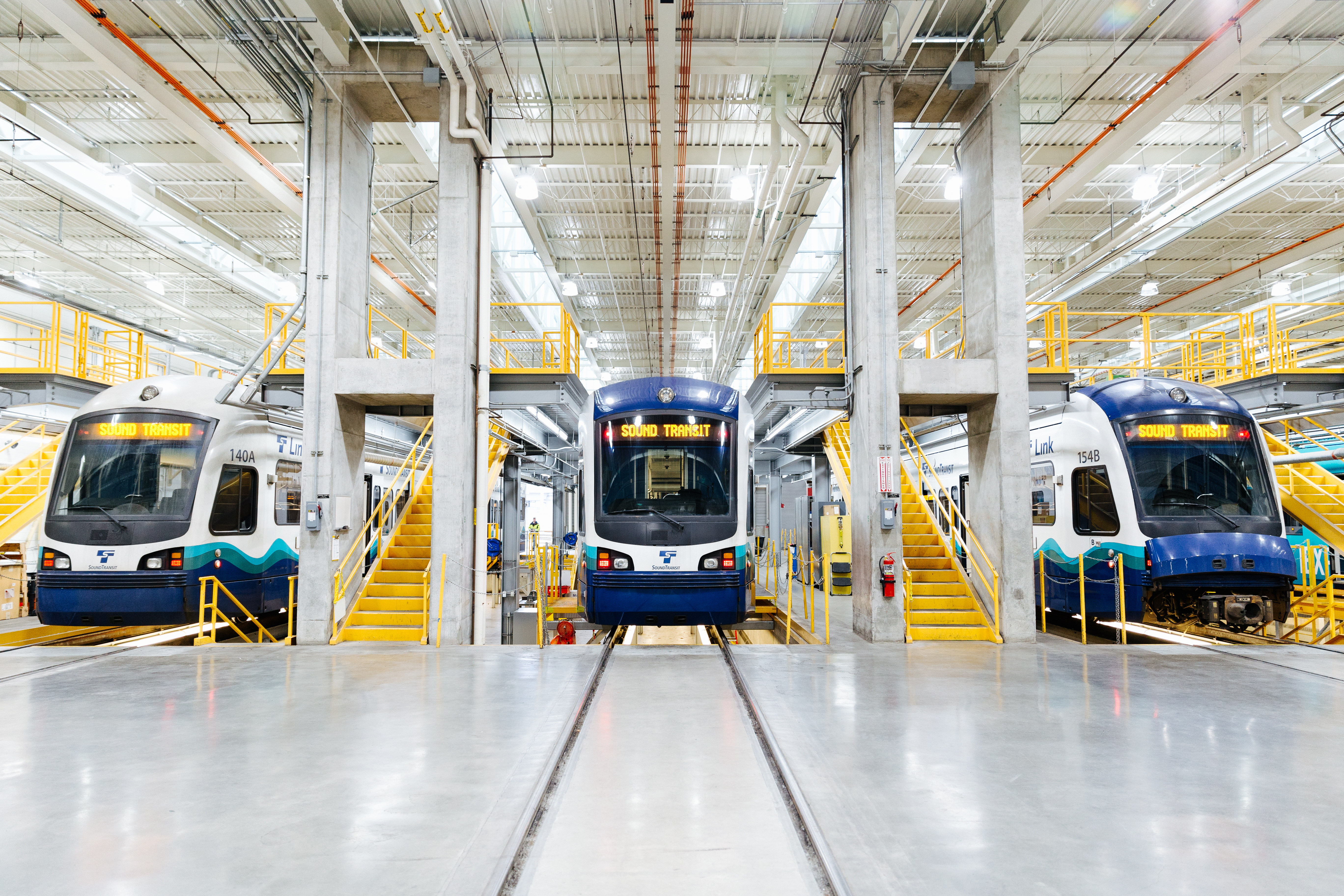 Link light rail trains are staged on maintenance platforms in the Link Storage Building. Stairs are provided on the platform so that workers can access both the top of the train and the underside of the train to perform routine maintenance.